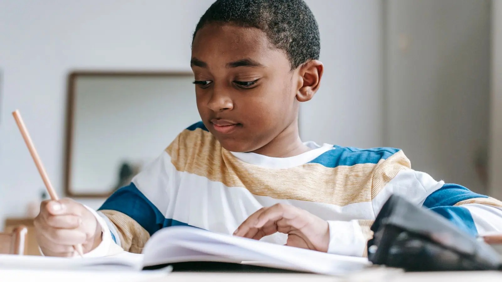 A young schoolboy writing in a notebook at a desk