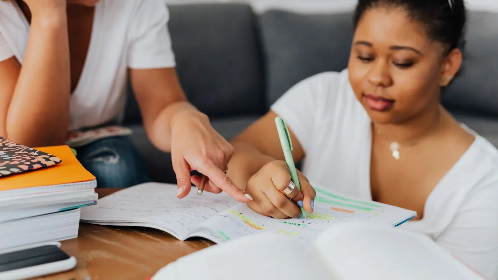 Two people working through notebooks together at a table during a one-to-one study session at home