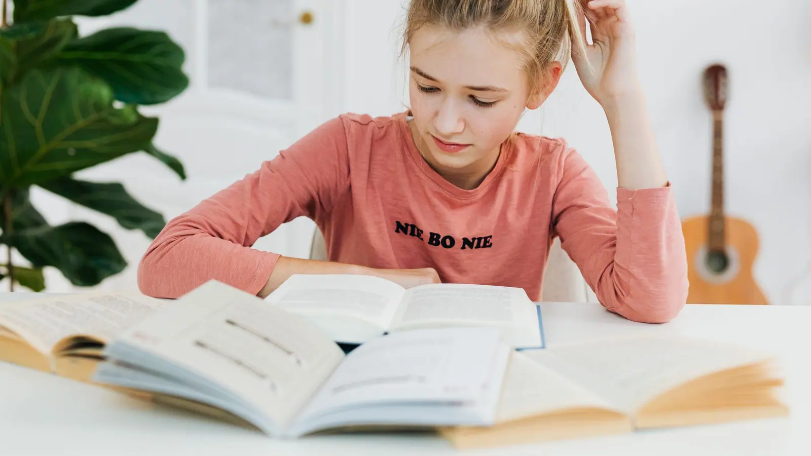 A teenage student studying with open textbooks at a bright desk